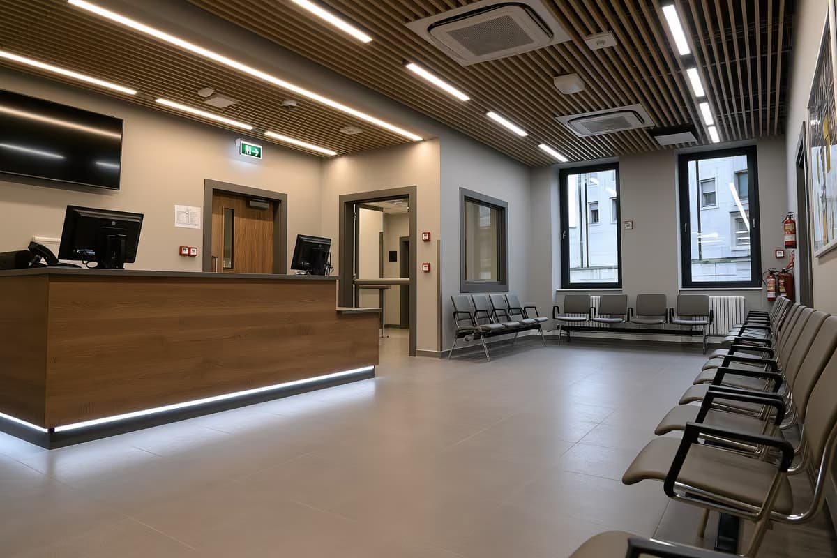 Oficialus aptarnavimo stalas ir tuščios laukiančiųjų kėdės tylioje viešojoje įstaigoje.
