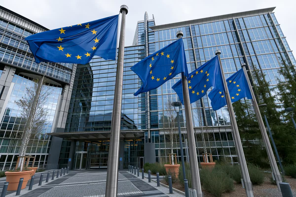 Europos Sąjungos vėliavos ant stiebų priešais modernų stiklinį pastatą.